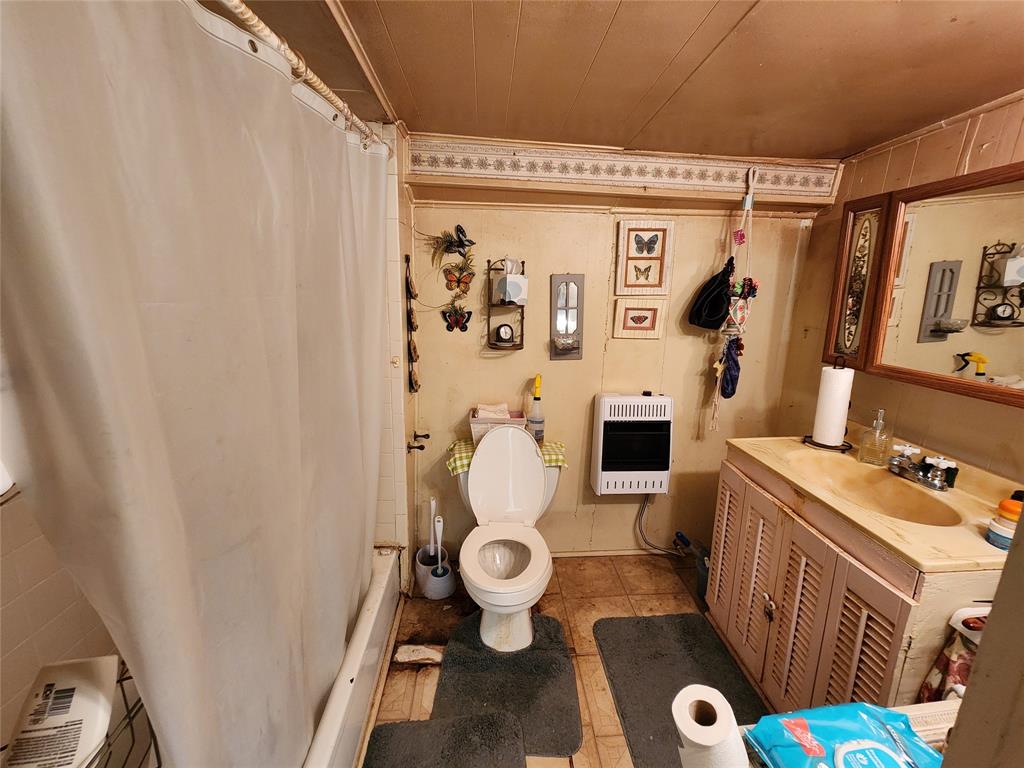 403 Barker Street Cumby, TX 75433 - Photo 9 of 16 Bathroom featuring a built-in tub with shower, toilet, and vanity with an integrated sink