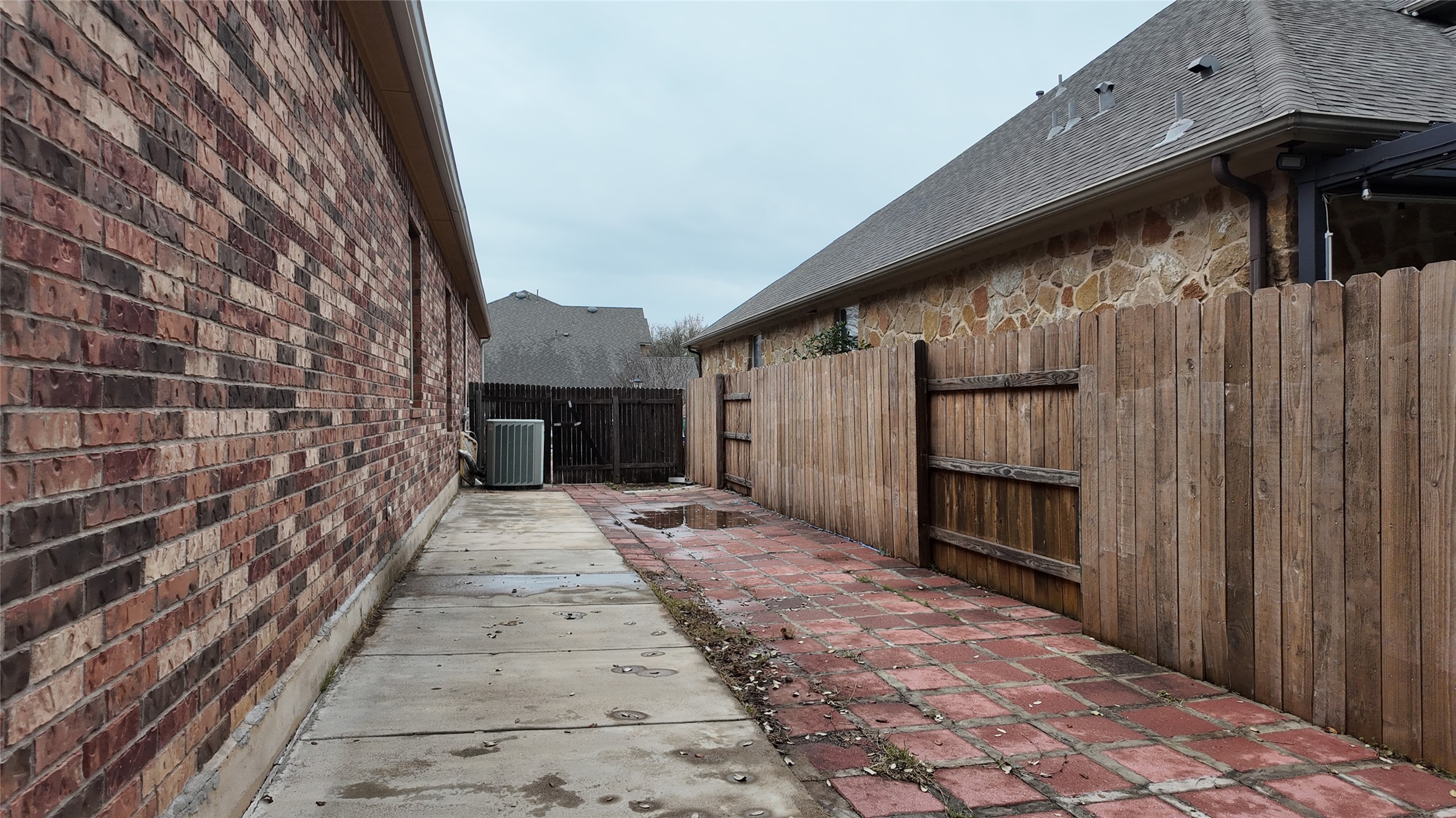 1601 Nelson Ranch Loop Cedar Park, TX 78613 - Photo 23 of 25 View of side of property featuring roof with shingles, a fenced backyard, stone siding, and brick siding