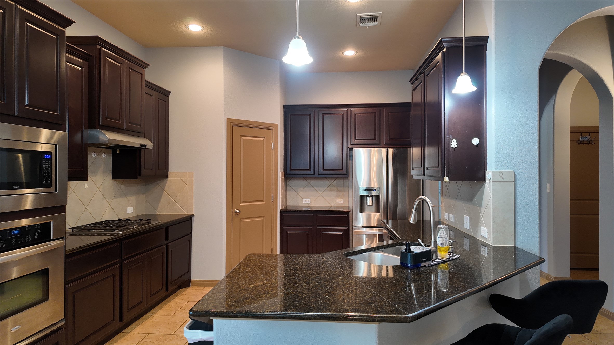 1601 Nelson Ranch Loop Cedar Park, TX 78613 - Photo 6 of 25 Kitchen featuring a breakfast bar area, stainless steel appliances, dark wood finish cabinets, and backsplash