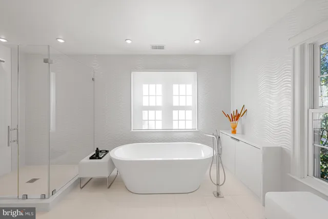 a spacious bathroom with a tub shower and windows