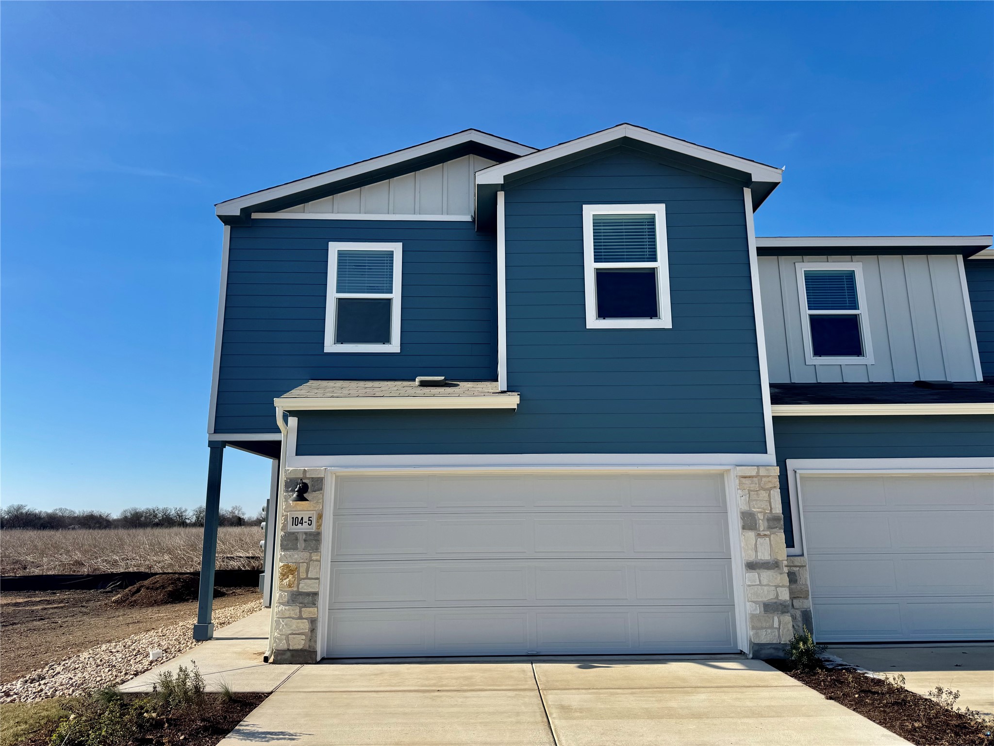 View of front of house featuring stone siding, board and batten siding, an attached garage, and concrete driveway