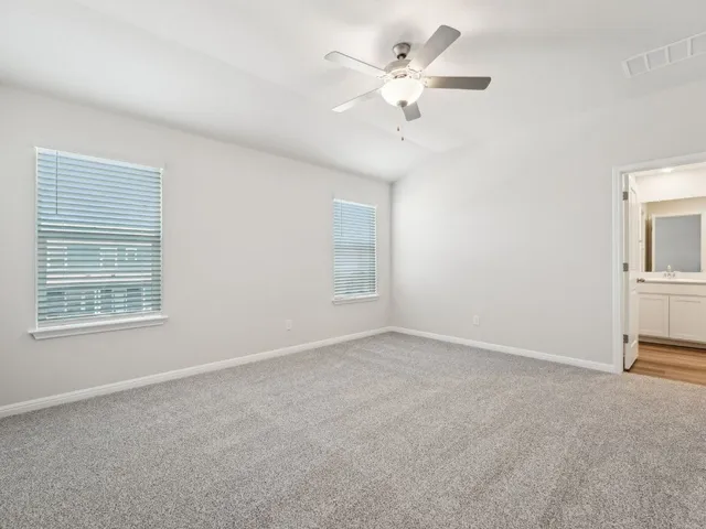 an empty room with a chandelier fan and windows