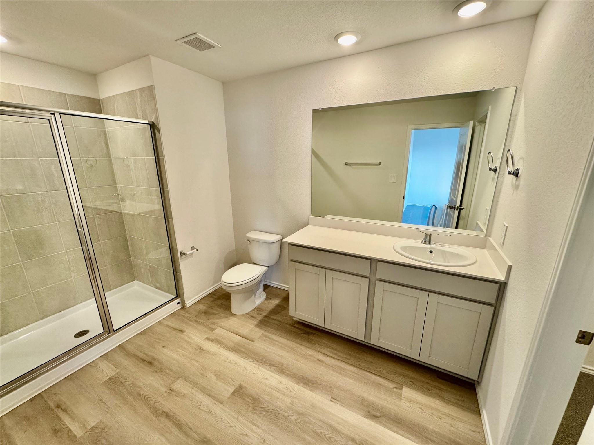 104 Calcite Road Kyle, TX 78640 - Photo 4 of 21 Full bath with vanity, a stall shower, light wood-style flooring, and recessed lighting