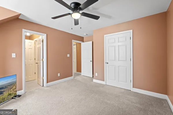 an empty room with closet and a ceiling fan