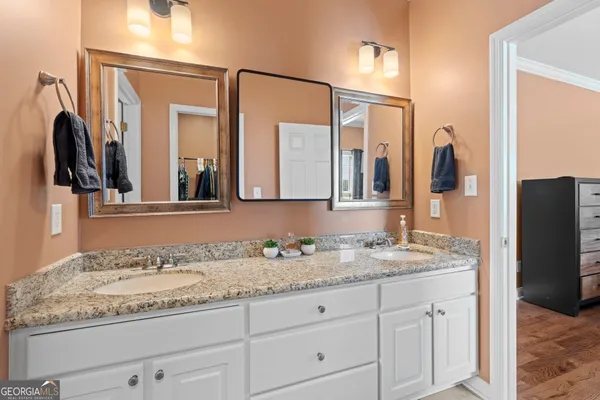 a bathroom with a granite countertop double vanity sink and a mirror