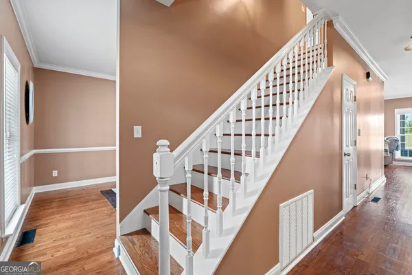 a view of staircase with wooden floor and white walls