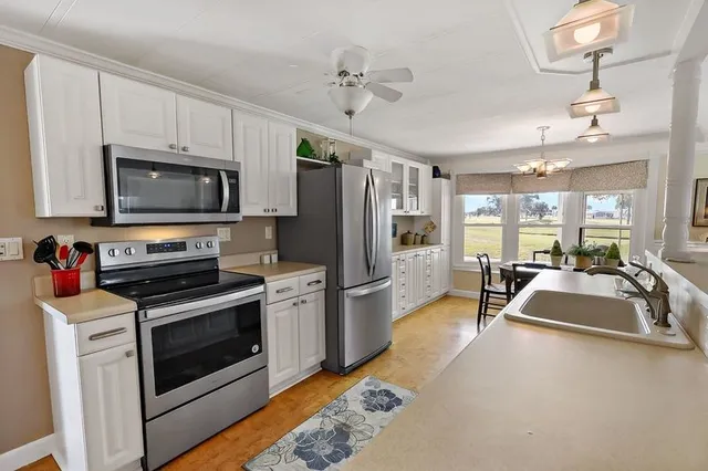 a large kitchen with stainless steel appliances a stove a refrigerator and a sink