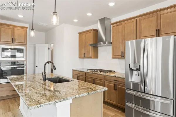 a kitchen with stainless steel appliances granite countertop a refrigerator a sink a stove and a refrigerator