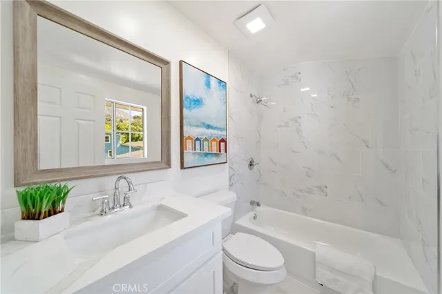 a bathroom with a granite countertop sink a toilet a tub and shower