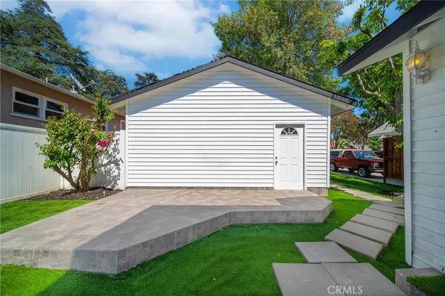 a backyard of a house with potted plants and large tree