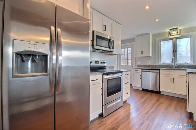 a kitchen with stainless steel appliances cabinets a wooden floor and a sink