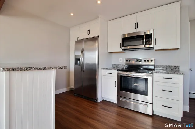 a kitchen with stainless steel appliances a stove a microwave and a hard wood floors