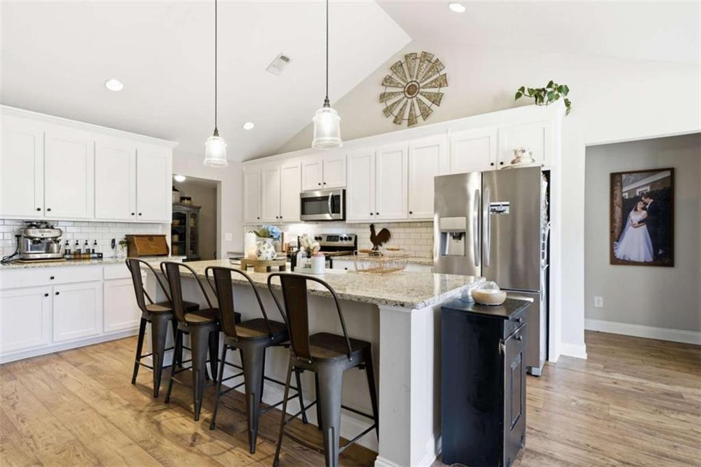 189 Marie Court Bethlehem, GA 30620 - Photo 30 of 57 a kitchen with stainless steel appliances kitchen island granite countertop a refrigerator a stove a sink a dining table and chairs with wooden floor