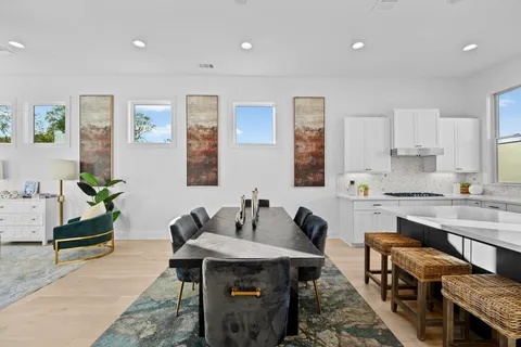 a kitchen with stainless steel appliances granite countertop a stove a sink dishwasher and white cabinets with wooden floor