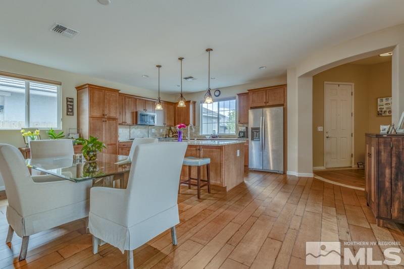 9840 Nahar Lane Reno, NV 89521 - Photo 4 of 25 a kitchen with stainless steel appliances granite countertop a refrigerator a stove top oven and a dining table with wooden floor