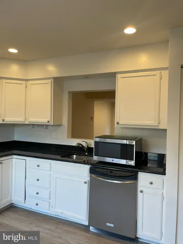 a kitchen with granite countertop white cabinets and black appliances