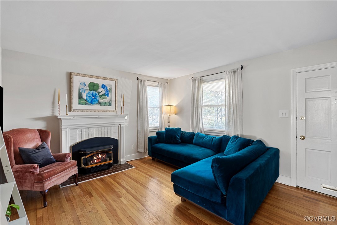 Living area with wood floors, a brick gas fireplac