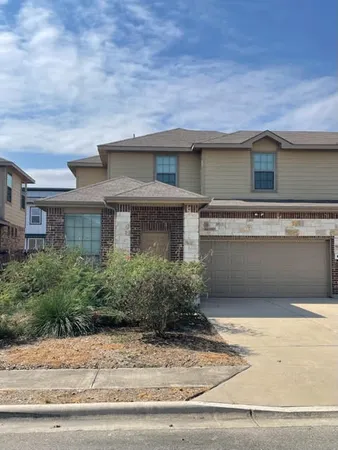 a front view of a house with garage and plants