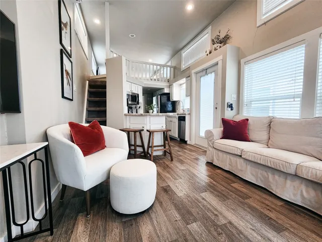 a living room with stainless steel appliances furniture and a kitchen view