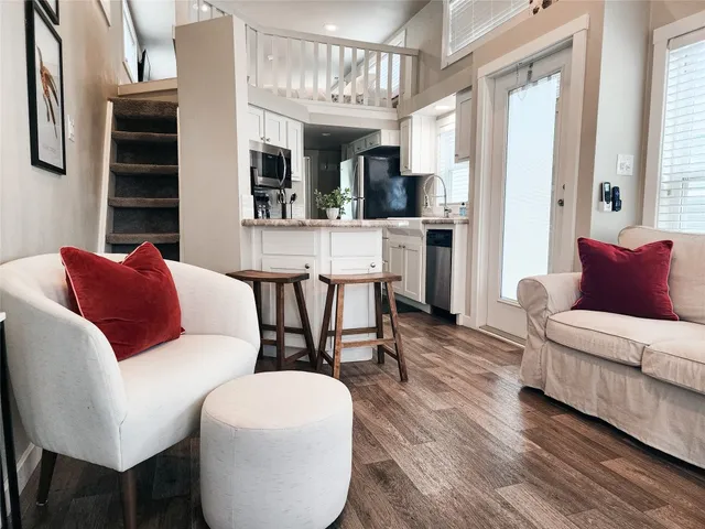 a living room with stainless steel appliances furniture and a kitchen view