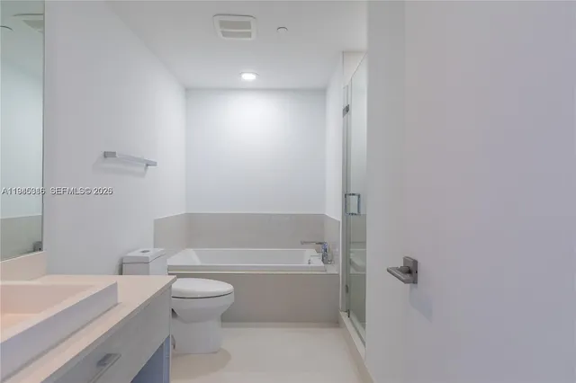 a bathroom with a bathtub shower sink mirror vanity and toilet