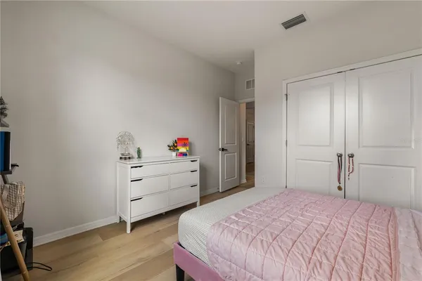 a view of a hallway with wooden floor and a bathroom
