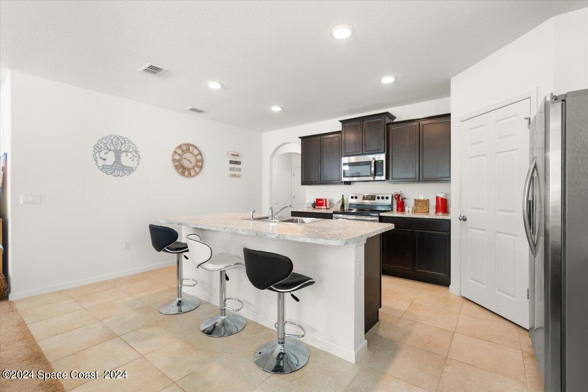 4332 Starling Place Mims, FL 32754 - Photo 6 of 28 a kitchen with a refrigerator and a dining table