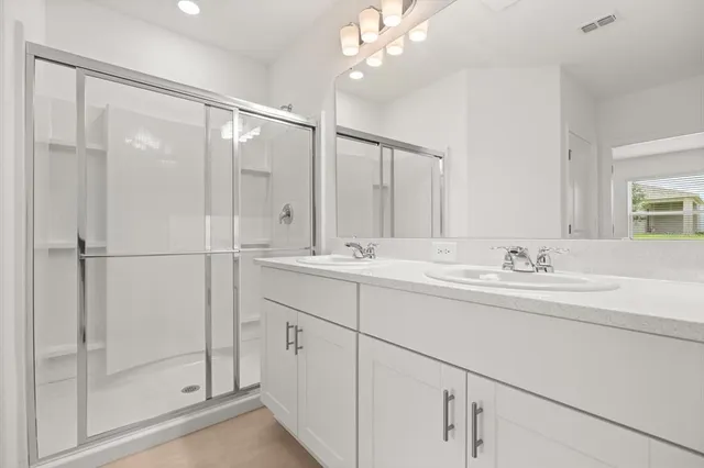 a bathroom with a double vanity sink mirror and shower