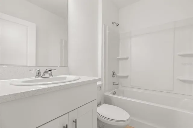 a bathroom with a bathtub shower sink vanity mirror and toilet