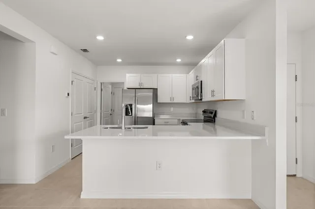 a kitchen with stainless steel appliances granite countertop a sink a refrigerator and a granite counter tops