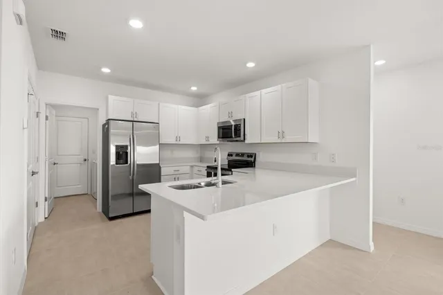 a kitchen with stainless steel appliances a refrigerator sink and white cabinets