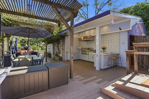 a view of a patio with table and chairs under an umbrella with a barbeque grill and couches