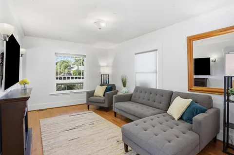 a living room with furniture a flat screen tv and a window