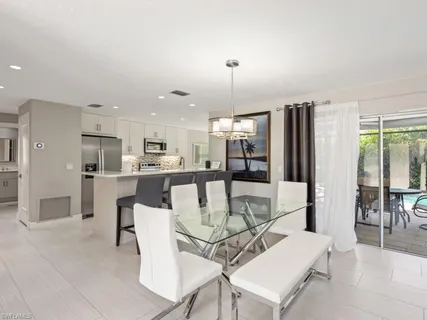 a view of a dining room with furniture a chandelier and kitchen view