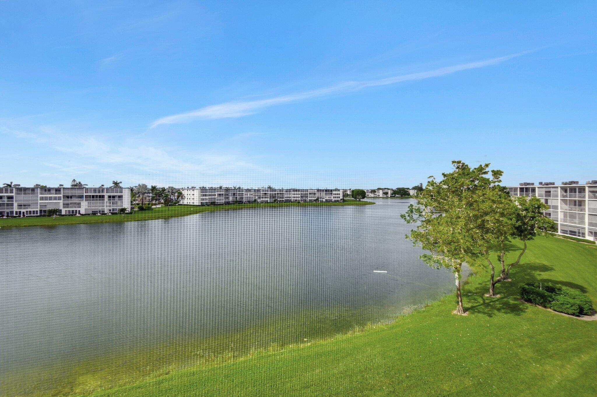 4089 Guildford East, Unit E Boca Raton, FL 33434 - Photo 2 of 22 a view of a lake with houses in the background