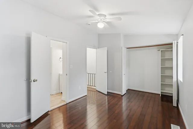 an empty room with wooden floor and a ceiling fan