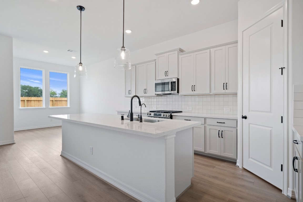 32107 Waterlily View Hockley, TX 77447 - Photo 6 of 21 a kitchen with kitchen island white cabinets a sink a window and appliances