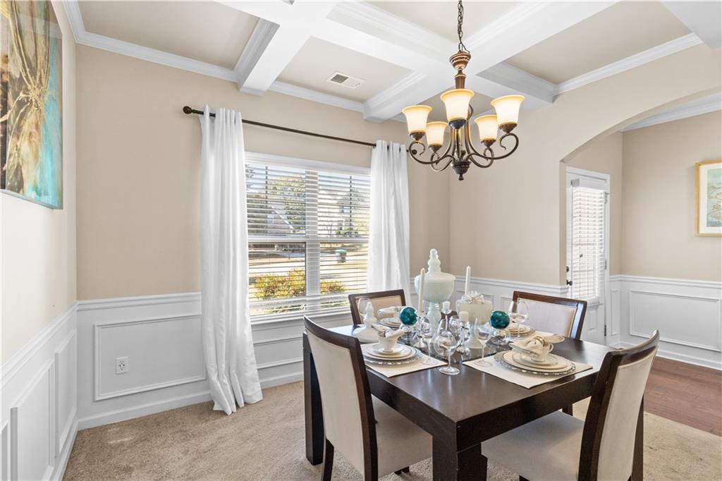 9116 Alden Drive Locust Grove, GA 30248 - Photo 7 of 27 a dining room with wooden floor a chandelier a wooden table and chairs