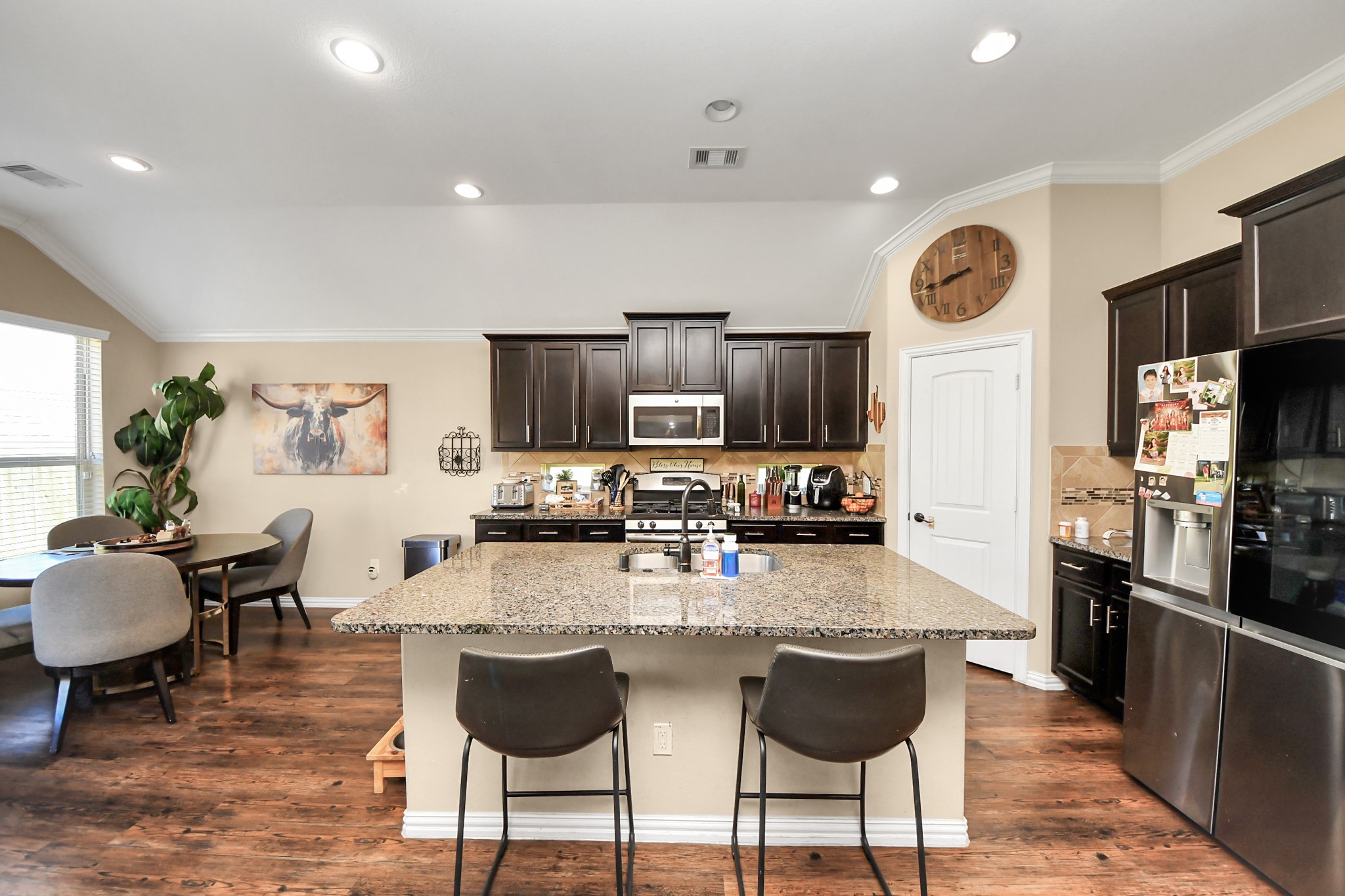 7502 Simpson Springs Lane Spring, TX 77389 - Photo 25 of 38 a kitchen with stainless steel appliances granite countertop a stove top oven a sink dishwasher a dining table and chairs with wooden floor