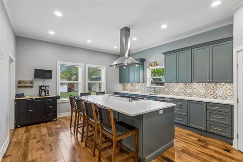 a kitchen with a stove a sink dishwasher a kitchen island with wooden cabinets and floor