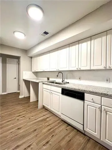 a large kitchen with kitchen island granite countertop a sink cabinets and wooden floor