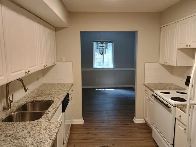 a kitchen with granite countertop a sink a stove and cabinets