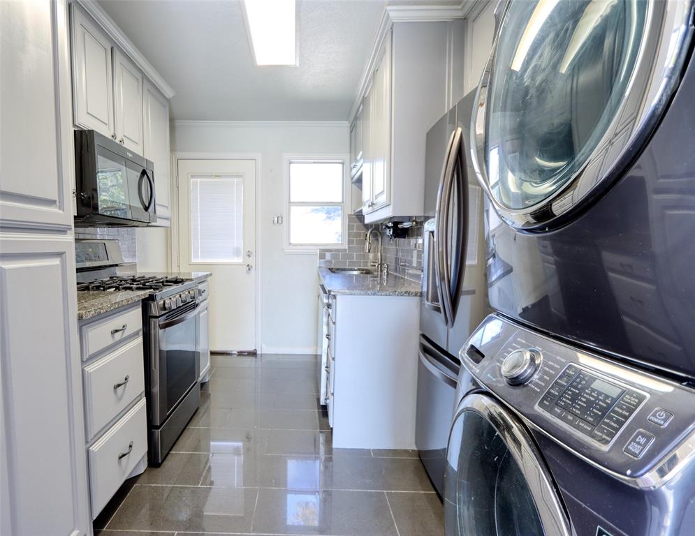 2222 Houston Street Grand Prairie, TX 75050 - Photo 5 of 24 a kitchen with stainless steel appliances granite countertop a stove a washer and dryer