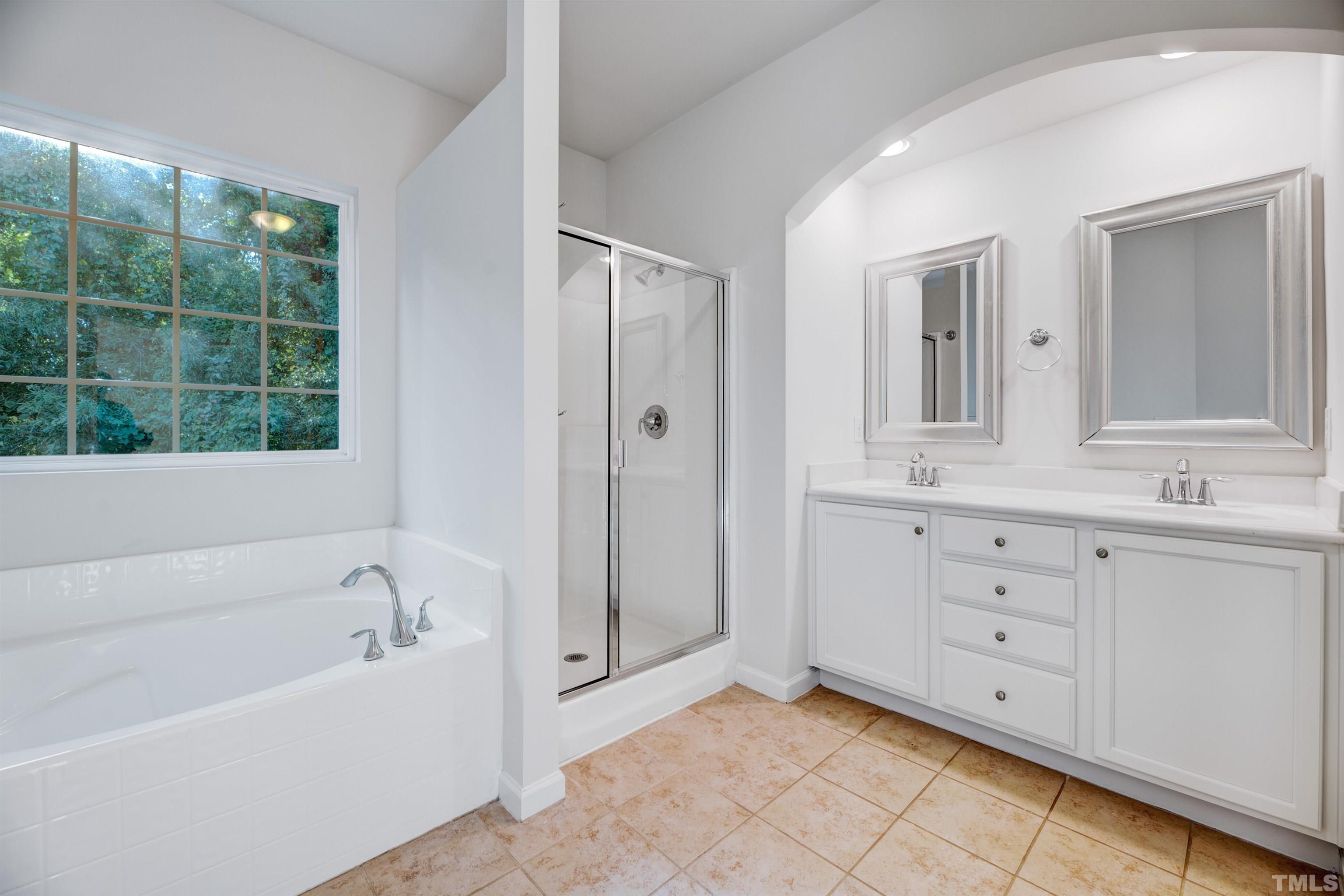 714 Treviso Lane Apex, NC 27502 - Photo 31 of 41 a bathroom with a bathtub a double vanity sink a vanity a window and a mirror
