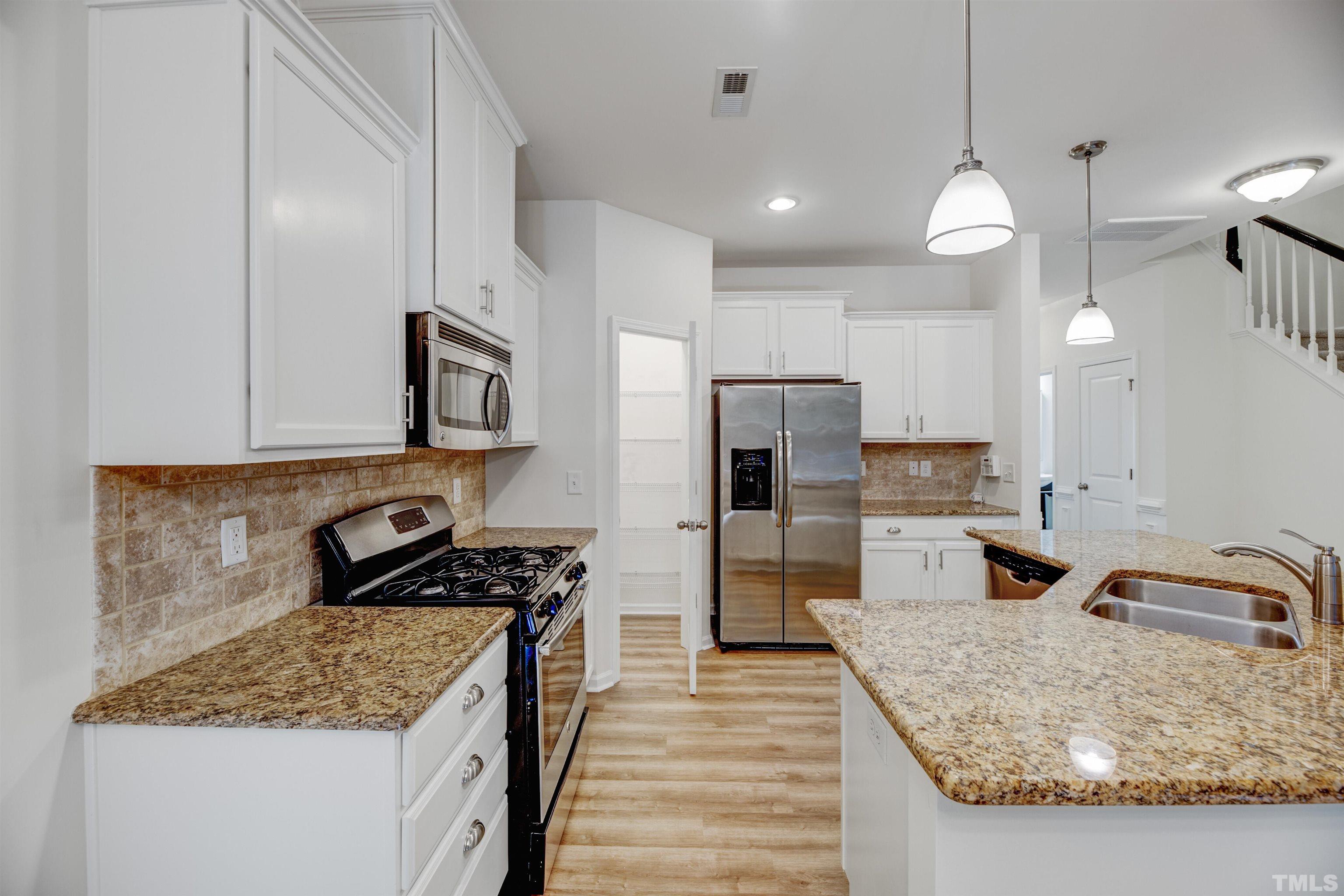 714 Treviso Lane Apex, NC 27502 - Photo 9 of 41 a kitchen with a refrigerator a sink a stove and cabinets