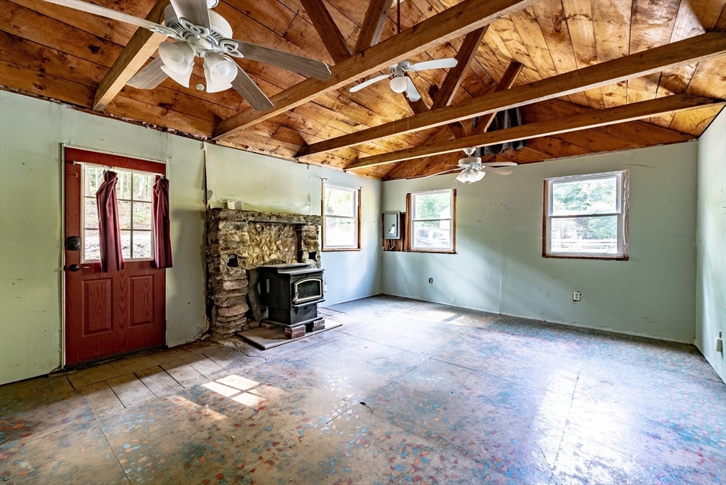 137 Rainbow Road Otis, MA 01029 - Photo 8 of 31 a view of an empty room with a fireplace and windows