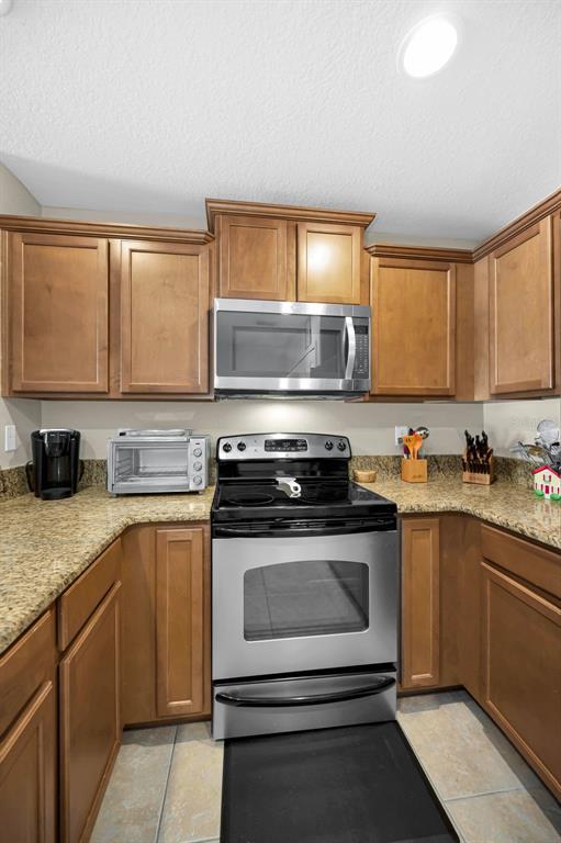 9736 Trumpet Vine Loop Trinity, FL 34655 - Photo 18 of 35 a kitchen with stainless steel appliances granite countertop a stove a sink and a microwave