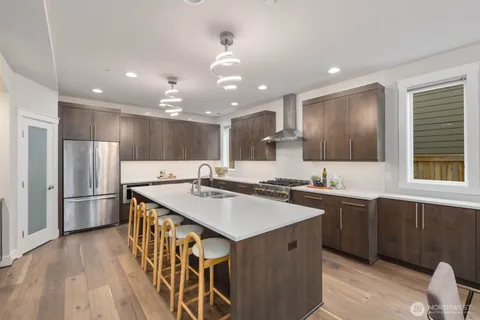 a kitchen with stainless steel appliances granite countertop a sink a stove a refrigerator and island with wooden floor