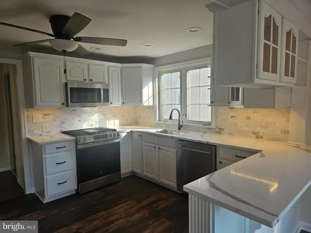 a kitchen with granite countertop a sink cabinets stainless steel appliances and a window