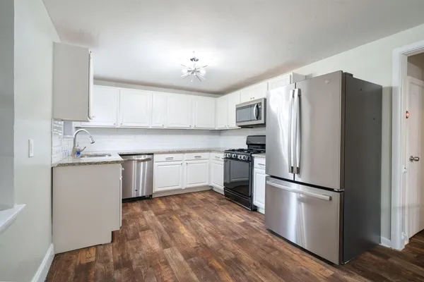 a kitchen with a refrigerator cabinets and wooden floor